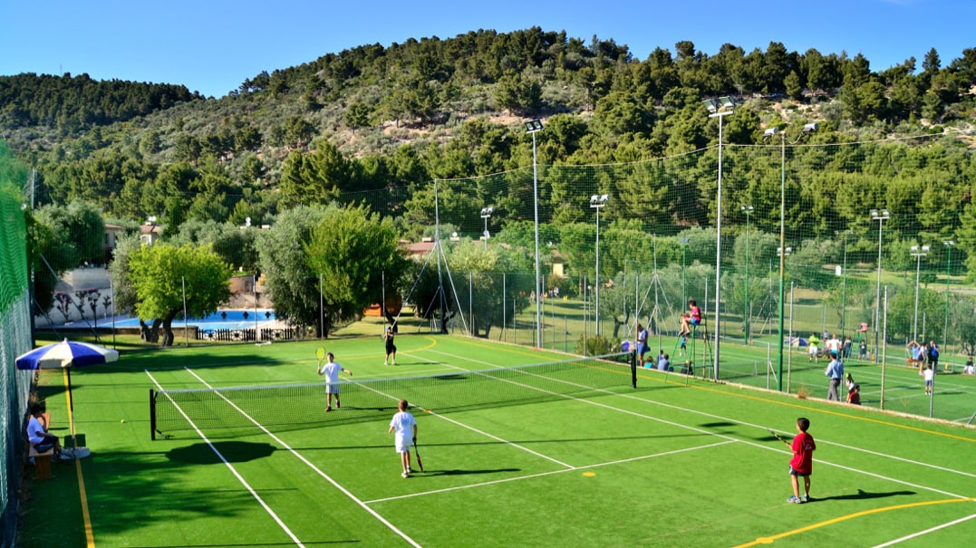 bambini che giocano a tennis su campo con erba sintetica